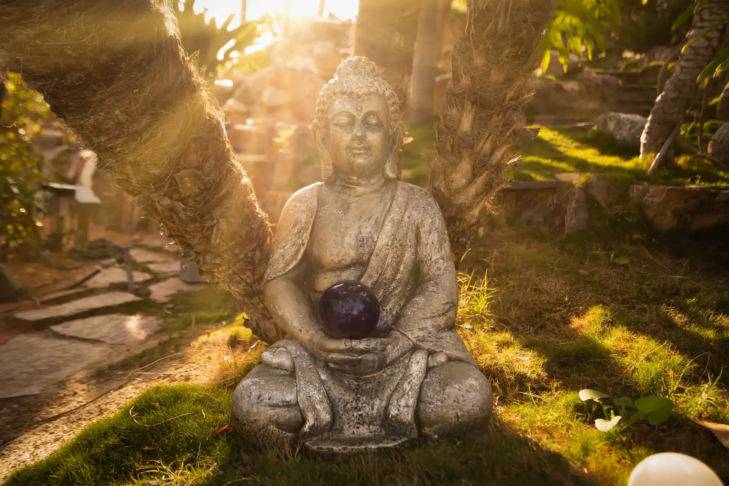 A shot of our statue of Buddha. Sunlight is peeking through the trees behind the statue, giving it a warm glow
