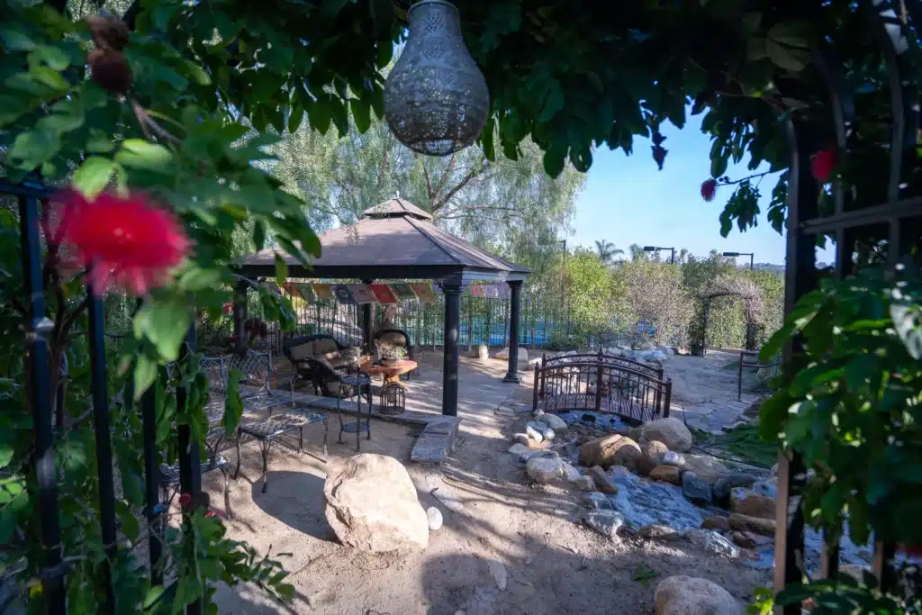 Villa Oasis gazebo with 4 chairs and a table underneath. There is a small bridge to cross over.