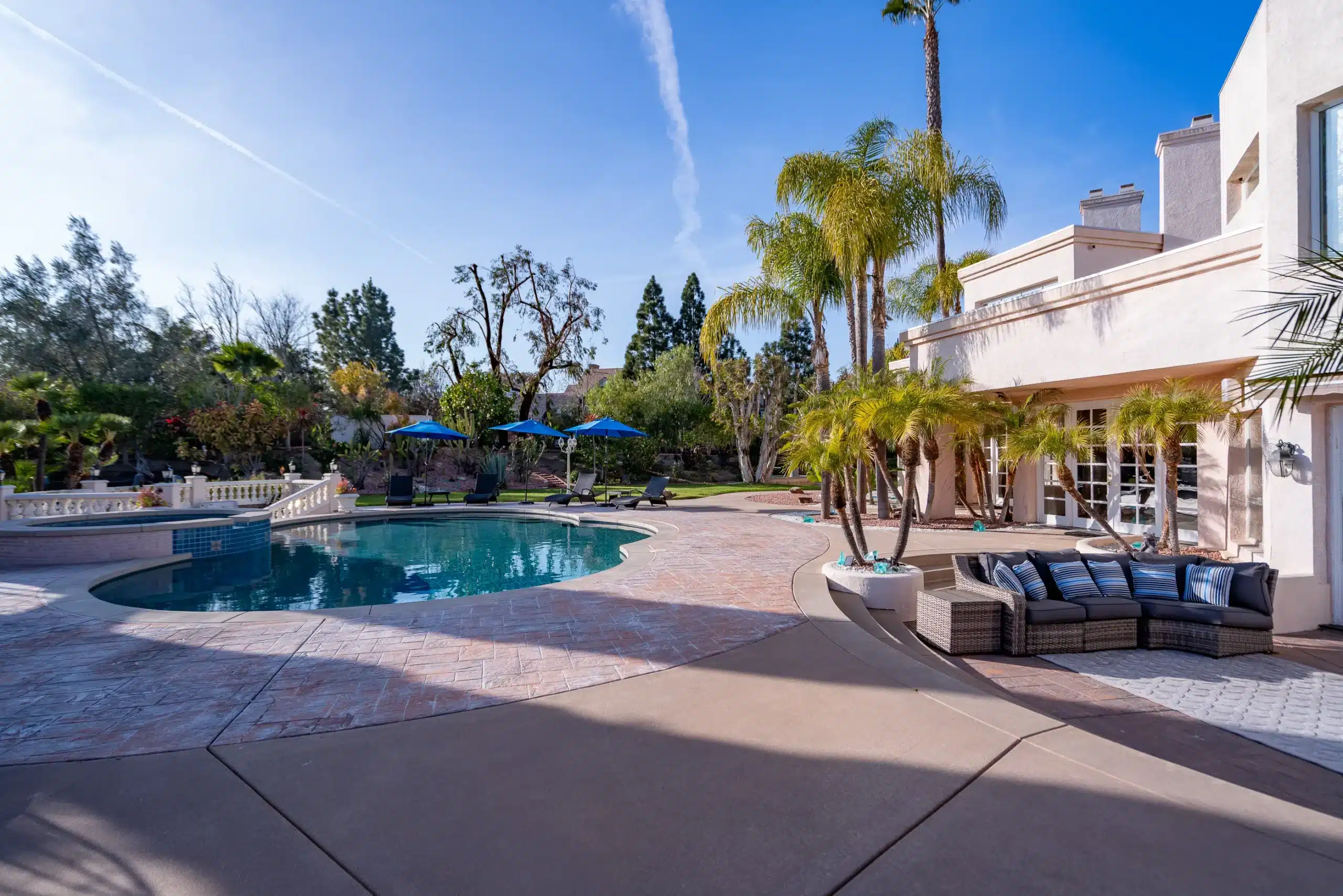 Villa Oasis backyard with pool and couch sitting area and lots of greenery