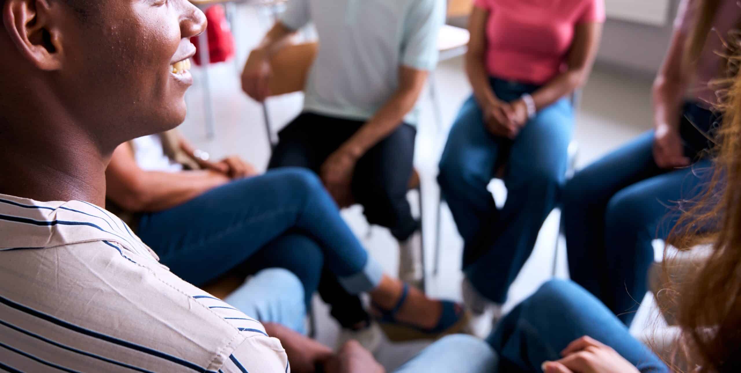 Group of multiracial high school students sitting on chairs in circle and interacting in classroom.