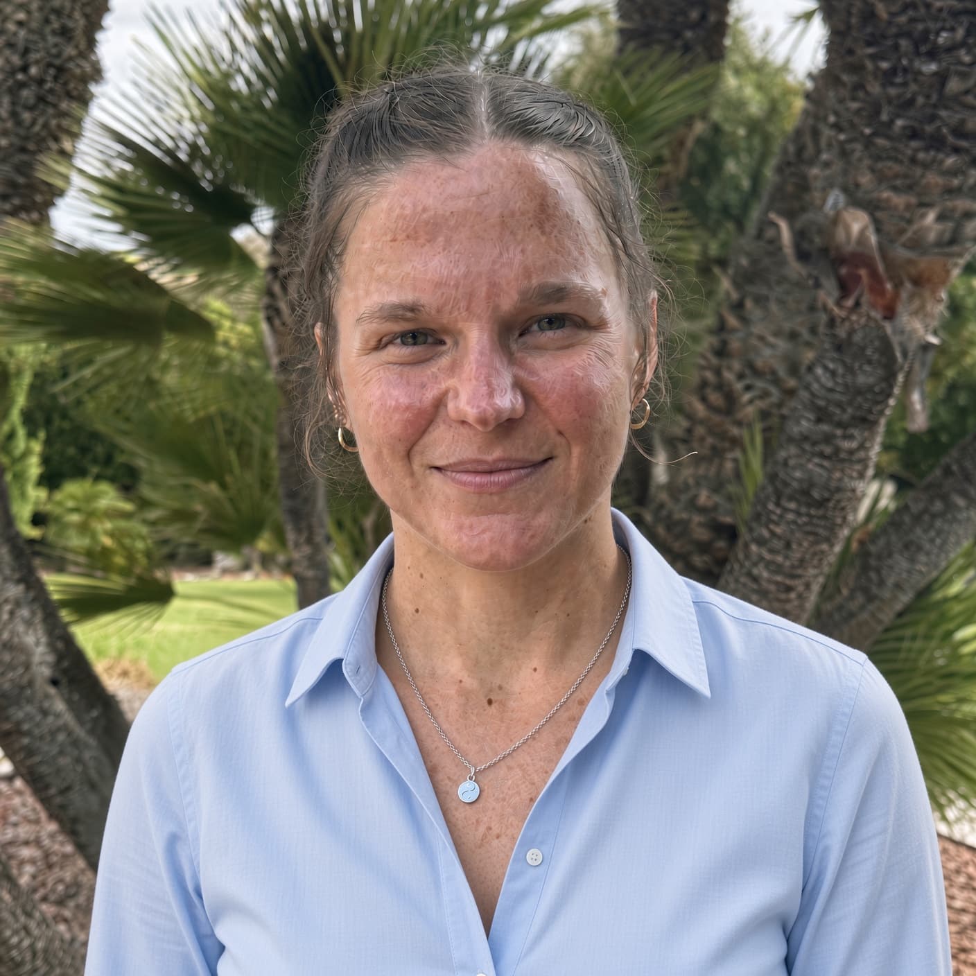 Michelle Beaupre, PhD, LCSW, smiling outdoors among palm trees at Villa Oasis