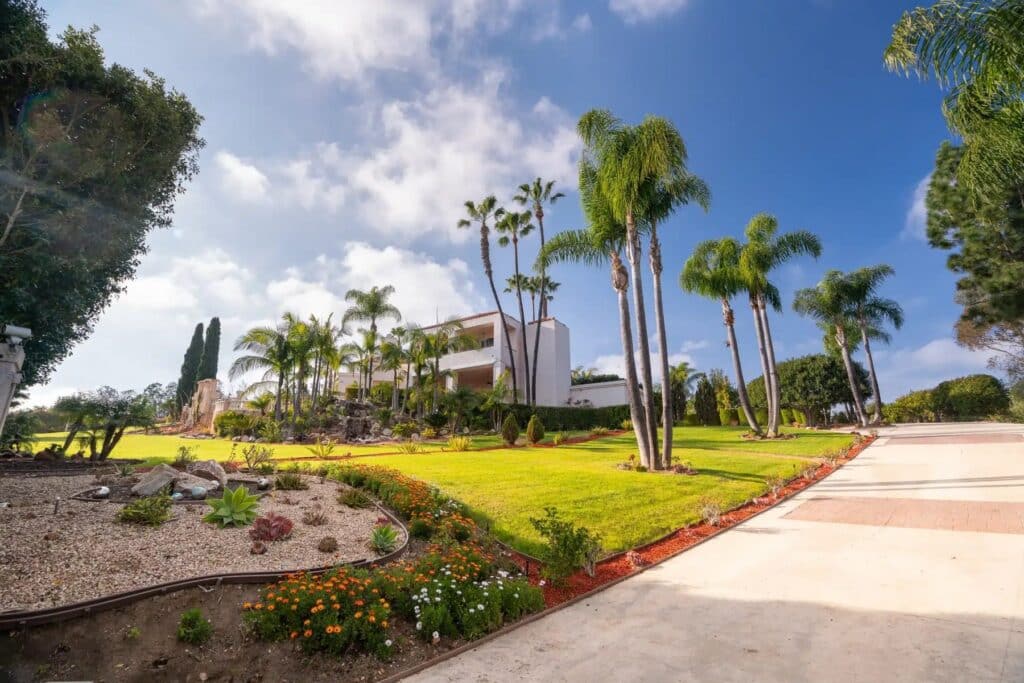 Landscaped lawns, flower beds and palm trees on the grounds of the Villa Oasis estate in Rancho Santa Fe
